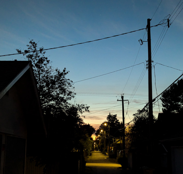 View down an urban lane towards the setting sun; includes C2PA data